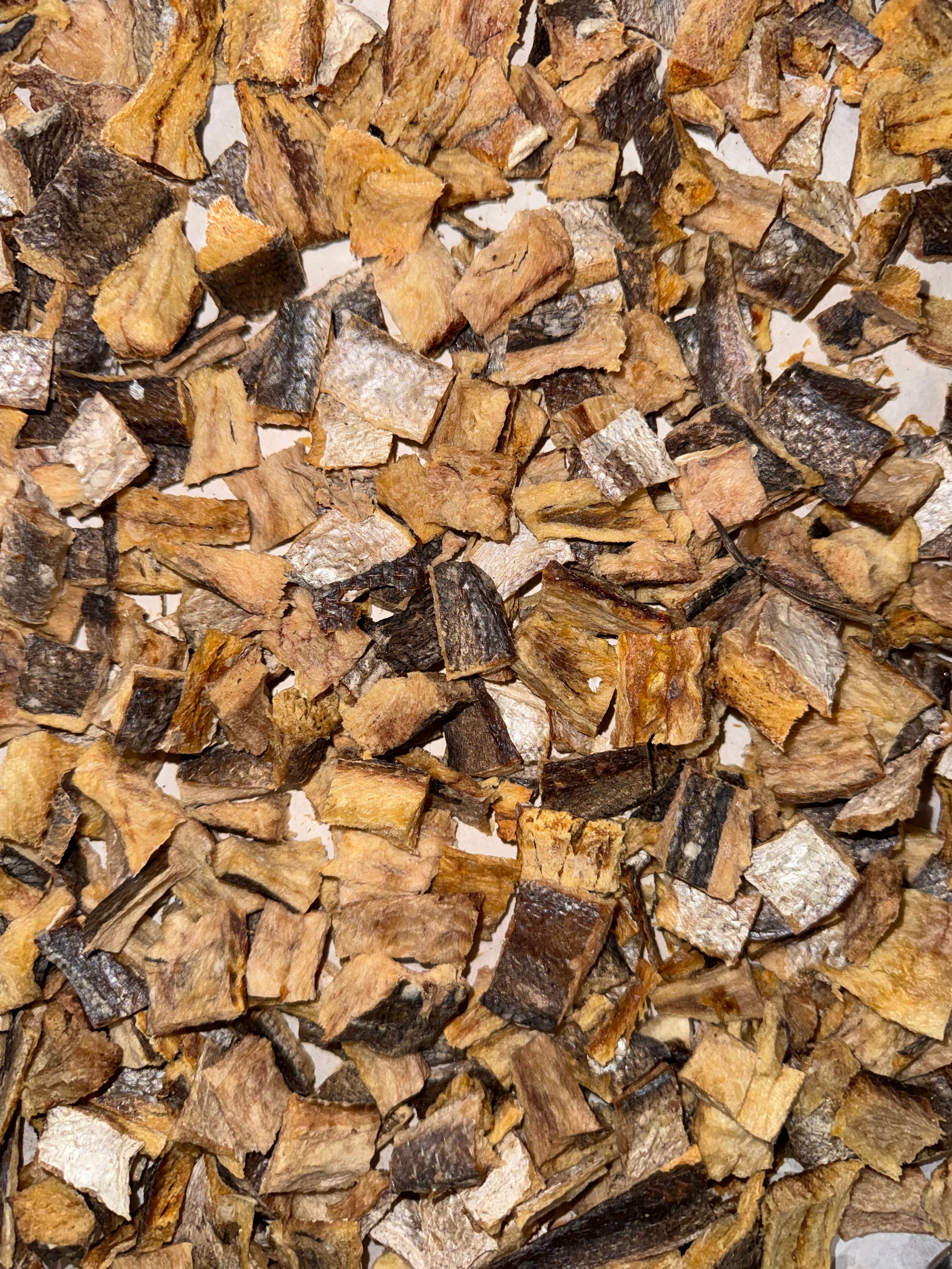A close-up, top-down view of dehydrated whiting fillets with skin, fish chips.